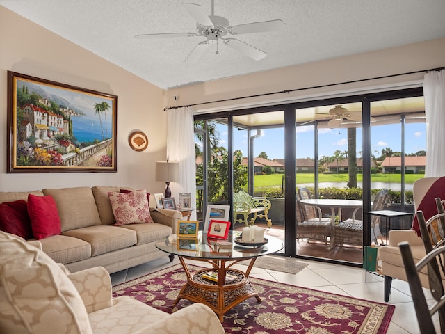 tiled living room featuring a water view, ceiling fan, a textured ceiling, and lofted ceiling