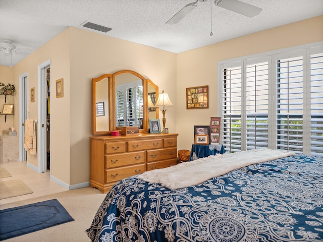 bedroom featuring connected bathroom, ceiling fan, a textured ceiling, and light colored carpet