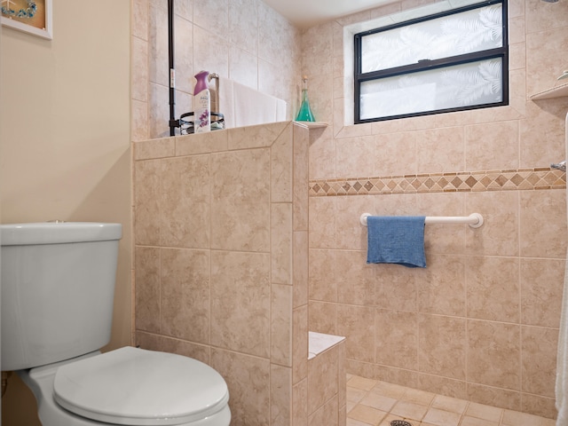 bathroom featuring toilet, tile patterned floors, and tiled shower