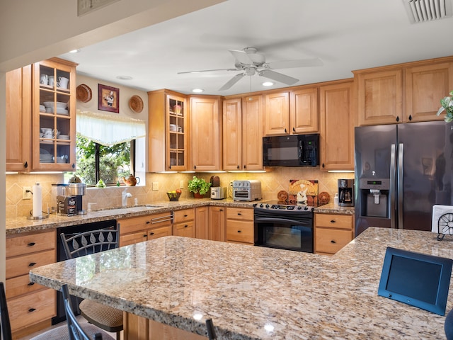 kitchen featuring light stone countertops, black appliances, sink, ceiling fan, and decorative backsplash