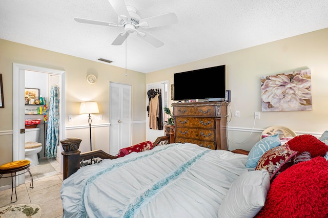 bedroom with ceiling fan, a textured ceiling, light tile patterned floors, and ensuite bath