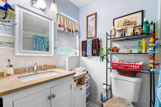 bathroom with tile walls, vanity, and toilet