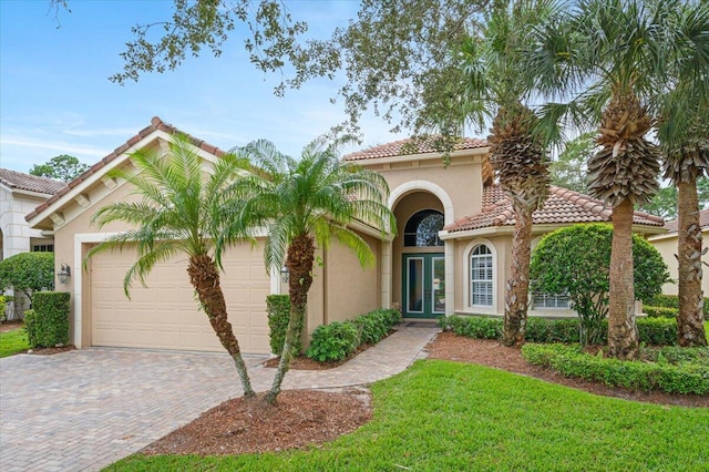 mediterranean / spanish house featuring a garage and a front lawn