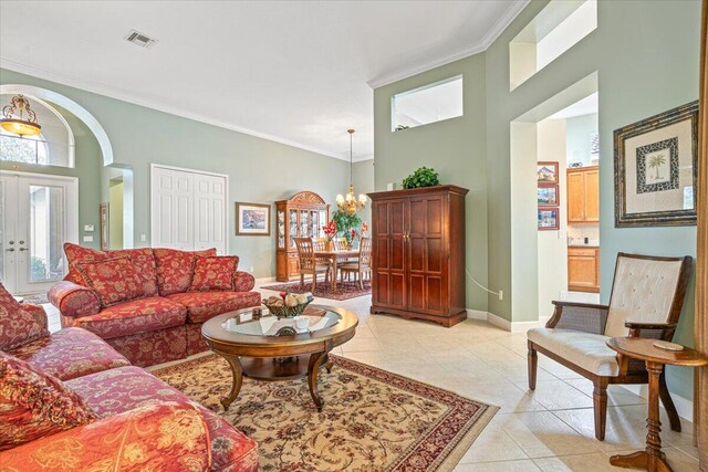 tiled living room featuring crown molding, a notable chandelier, a high ceiling, and french doors