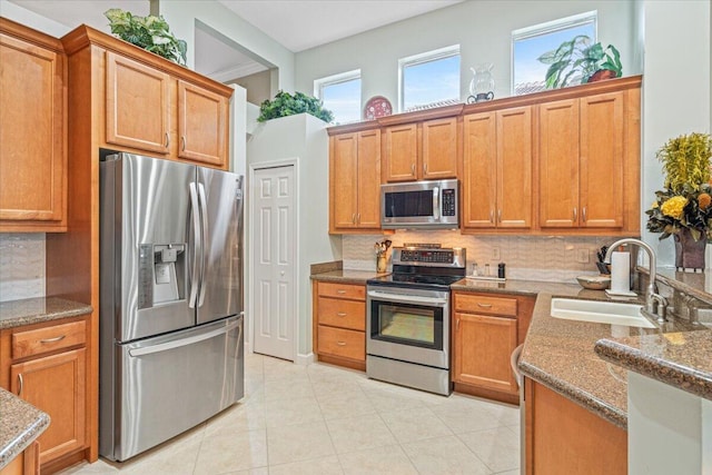 kitchen with sink, appliances with stainless steel finishes, decorative backsplash, and dark stone counters