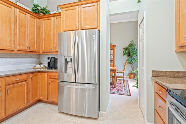 kitchen featuring light stone countertops, stainless steel appliances, backsplash, and light tile patterned floors