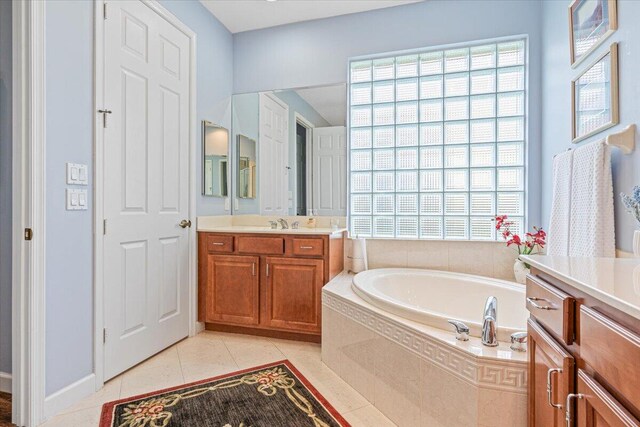 bathroom featuring vanity, tiled tub, and tile patterned flooring