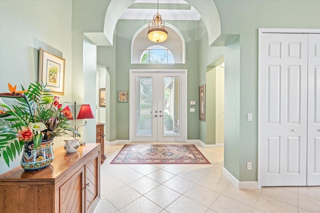 foyer entrance featuring french doors, a towering ceiling, and light tile patterned floors