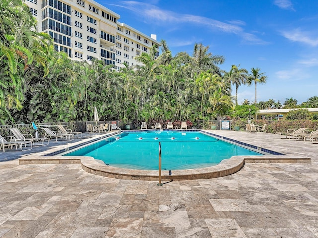 community pool with a patio and fence