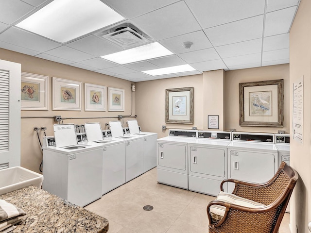 laundry room with light tile patterned flooring, sink, and washing machine and clothes dryer