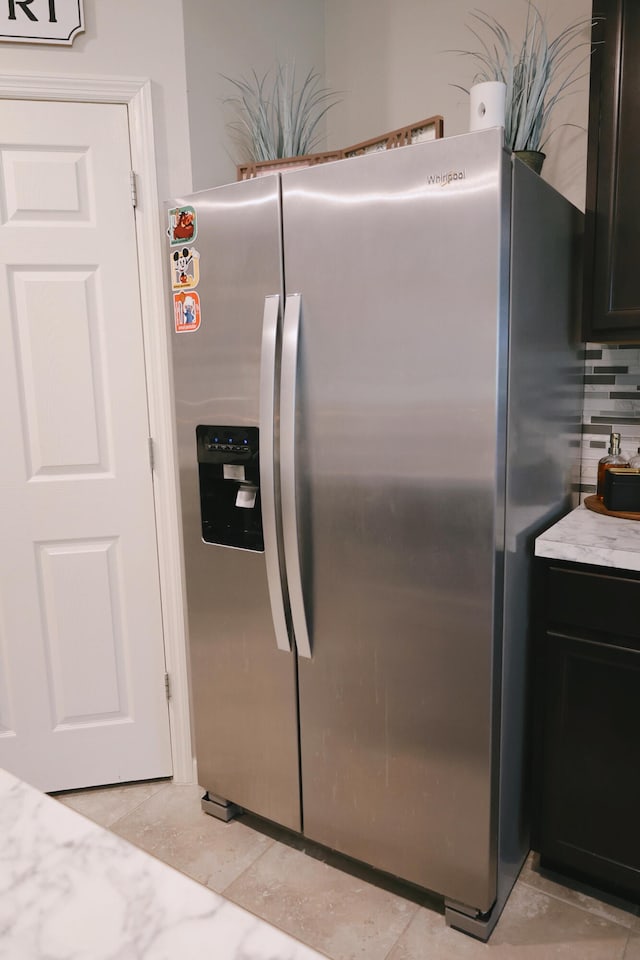 kitchen featuring backsplash, light tile patterned floors, and stainless steel fridge