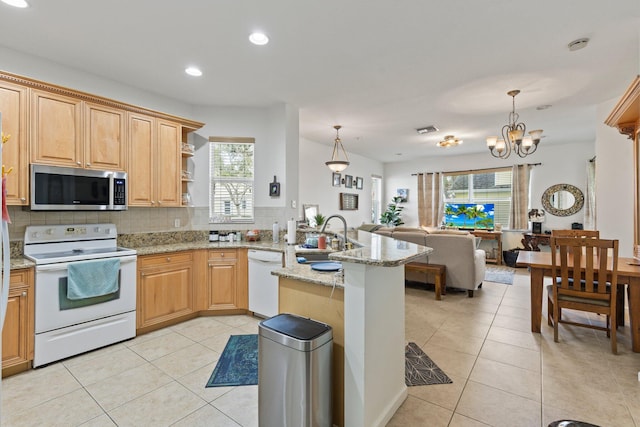 kitchen featuring sink, kitchen peninsula, pendant lighting, white appliances, and backsplash