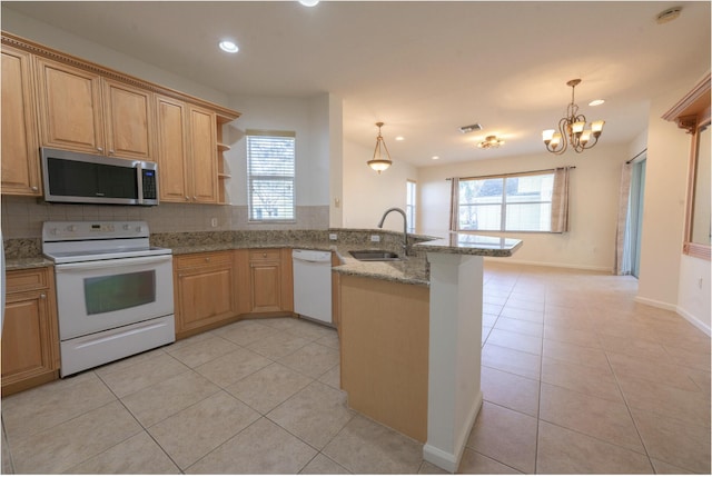 kitchen with decorative light fixtures, sink, white appliances, and kitchen peninsula