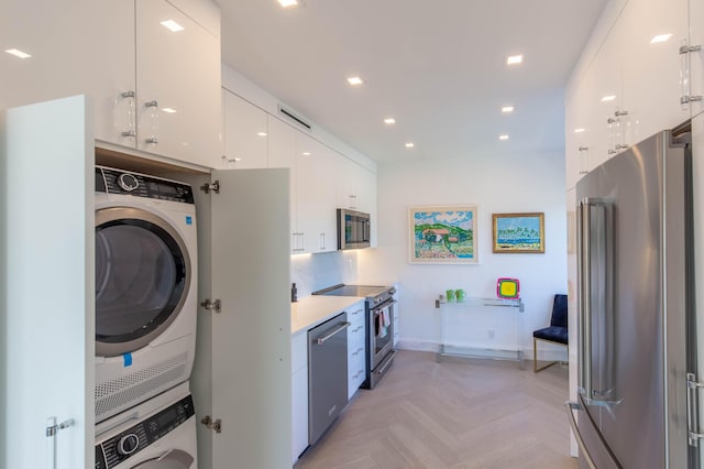 kitchen featuring modern cabinets, appliances with stainless steel finishes, stacked washing maching and dryer, white cabinetry, and recessed lighting