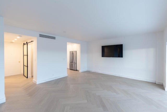 unfurnished living room featuring a barn door and light parquet flooring