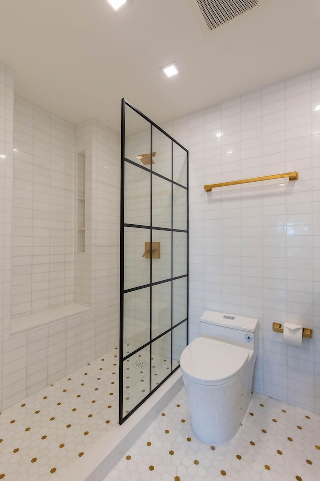 bathroom featuring toilet, tile walls, and tiled shower