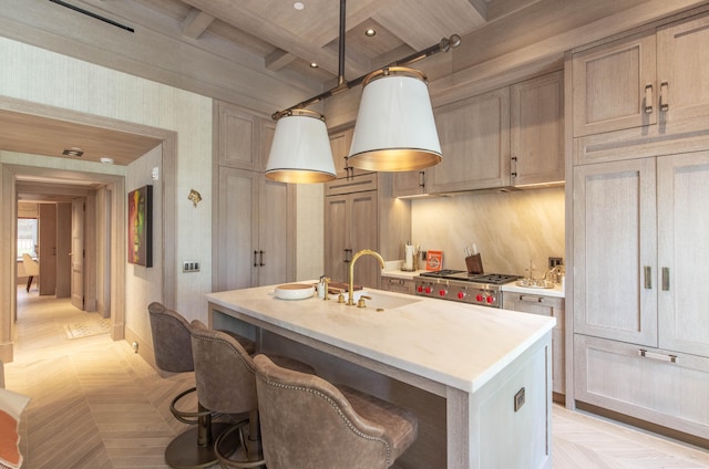 kitchen featuring light parquet floors, stainless steel range oven, sink, and an island with sink