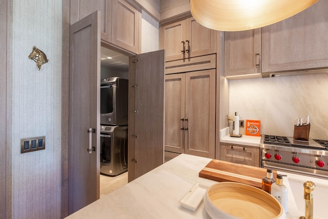 kitchen featuring stacked washing maching and dryer, light wood-type flooring, light brown cabinets, and stainless steel stove