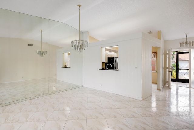 spare room with vaulted ceiling, sink, and a notable chandelier