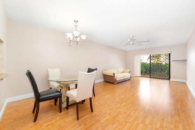 dining area with ceiling fan with notable chandelier and light hardwood / wood-style floors