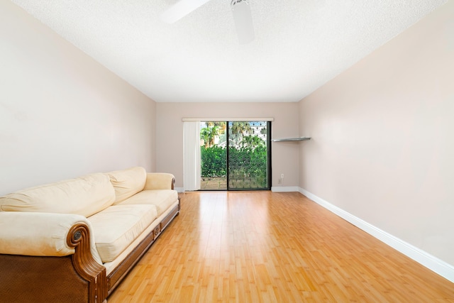 unfurnished living room with ceiling fan, a textured ceiling, and light wood-type flooring