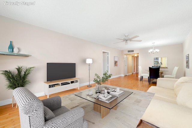 living room with hardwood / wood-style flooring and ceiling fan with notable chandelier