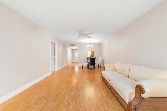 living room featuring ceiling fan with notable chandelier and light wood-type flooring