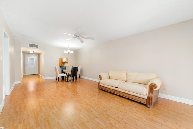 living room featuring ceiling fan with notable chandelier and light wood-type flooring