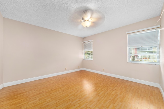 empty room with ceiling fan, a textured ceiling, and light wood-type flooring