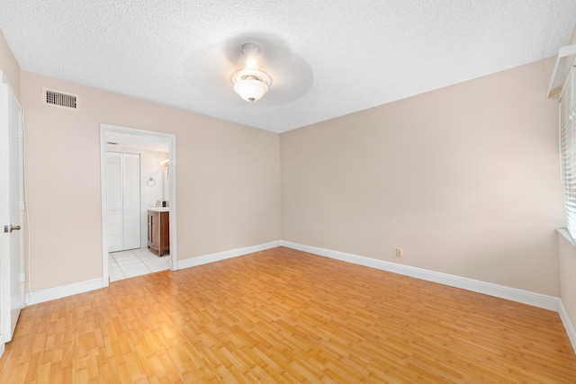 spare room with light hardwood / wood-style flooring and a textured ceiling