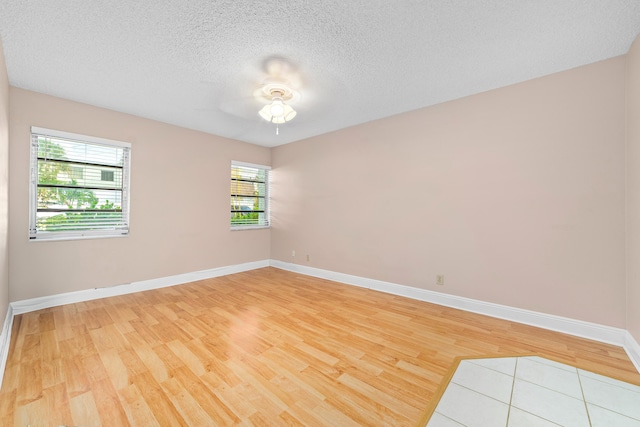 empty room with ceiling fan, light hardwood / wood-style flooring, and a textured ceiling