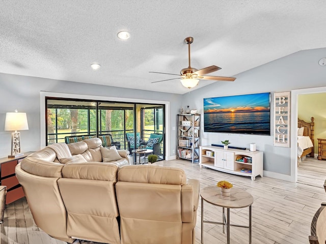 living room featuring lofted ceiling, a textured ceiling, light wood-type flooring, and ceiling fan