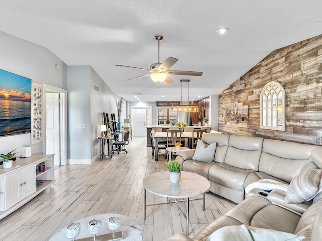 living room with wood walls, lofted ceiling, light wood-type flooring, and ceiling fan