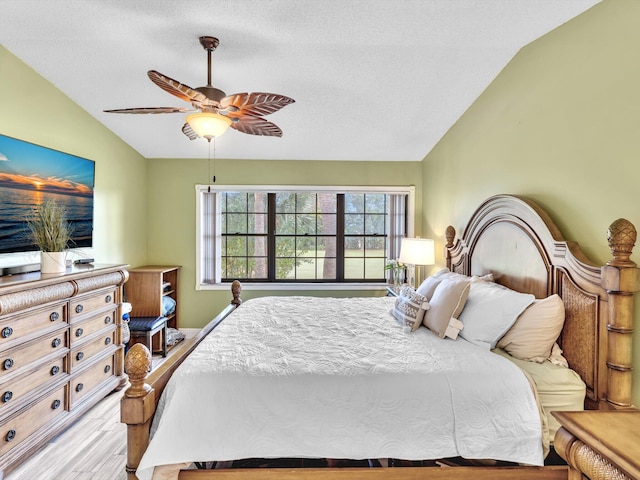 bedroom with ceiling fan, a textured ceiling, lofted ceiling, and light wood-type flooring