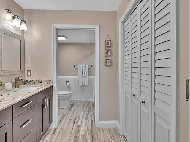 bathroom with toilet, vanity, and wood-type flooring