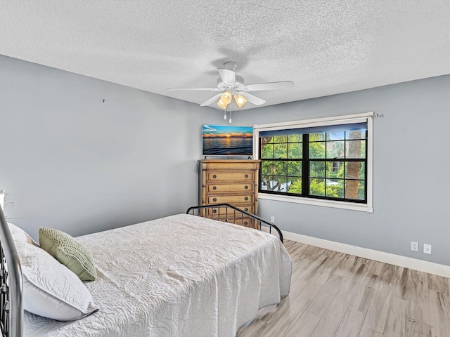 bedroom featuring ceiling fan, a textured ceiling, and light hardwood / wood-style flooring