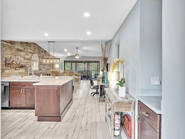 kitchen featuring dishwasher, sink, light wood-type flooring, and pendant lighting