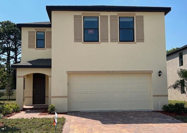 traditional-style house with a garage, driveway, and stucco siding