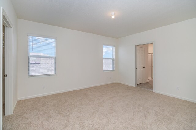 unfurnished bedroom featuring light carpet and multiple windows