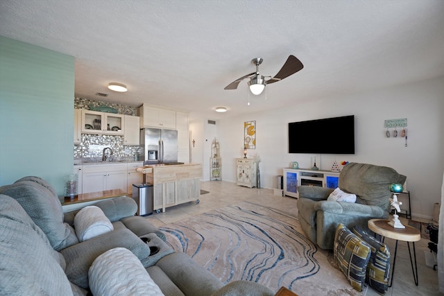 tiled living room with ceiling fan, a textured ceiling, and sink