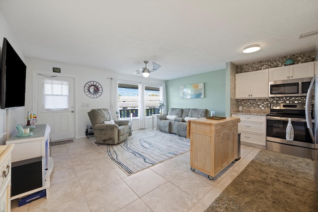 kitchen with tasteful backsplash, a kitchen island, white cabinetry, ceiling fan, and stainless steel appliances