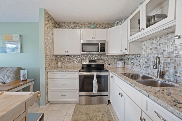 kitchen with decorative backsplash, appliances with stainless steel finishes, white cabinetry, a textured ceiling, and sink