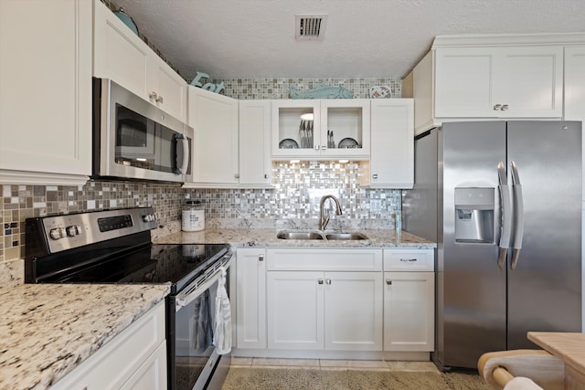 kitchen with sink, backsplash, stainless steel appliances, white cabinets, and light stone counters