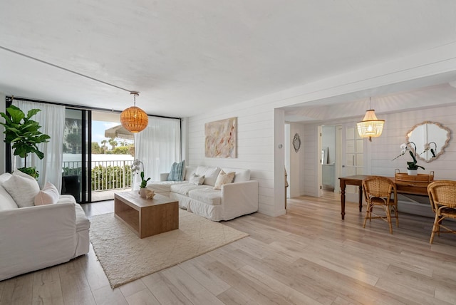 living room with wood walls, light hardwood / wood-style floors, and floor to ceiling windows