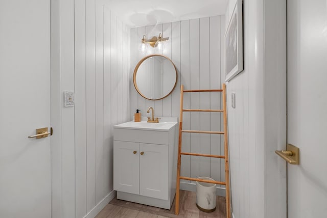 bathroom with vanity, wood-type flooring, and wooden walls