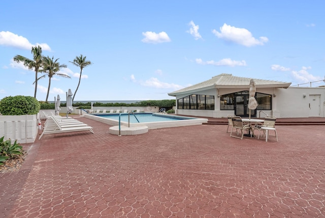 view of swimming pool with a sunroom and a patio