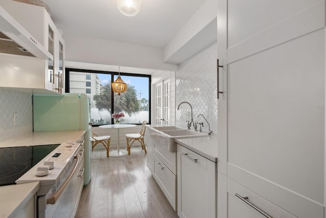 kitchen with white cabinets, electric range oven, sink, and tasteful backsplash