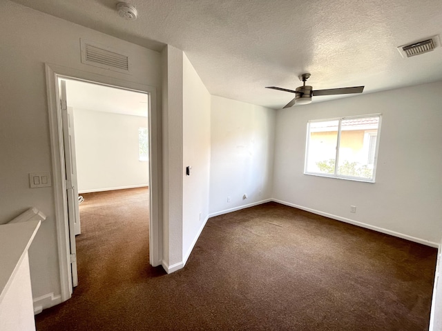 spare room featuring ceiling fan, a textured ceiling, and dark carpet