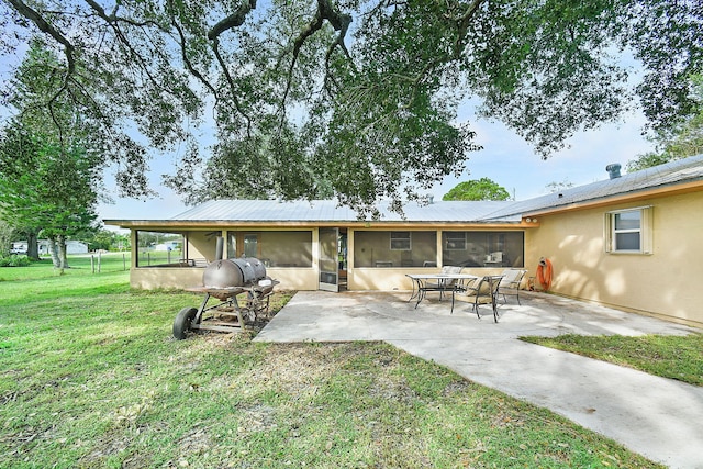 rear view of property featuring a patio, a sunroom, and a yard