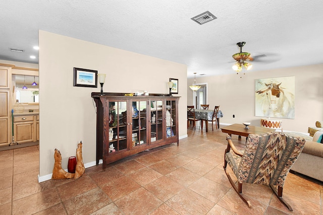 living room featuring a textured ceiling and ceiling fan